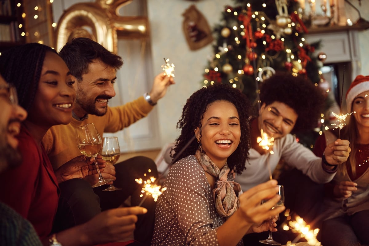 Cheerful friends having fun with sparklers during Christmas party at home