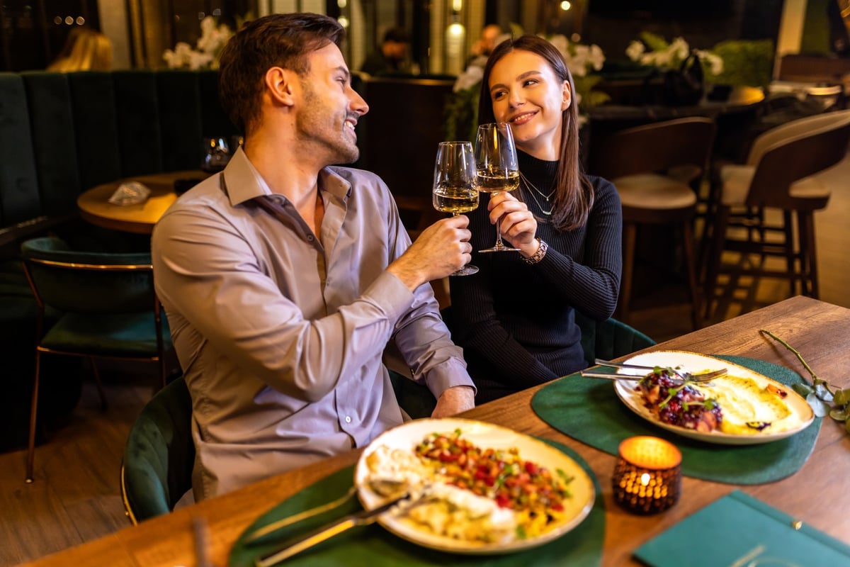 Hands of man and woman toasting with white wine in the restaurant