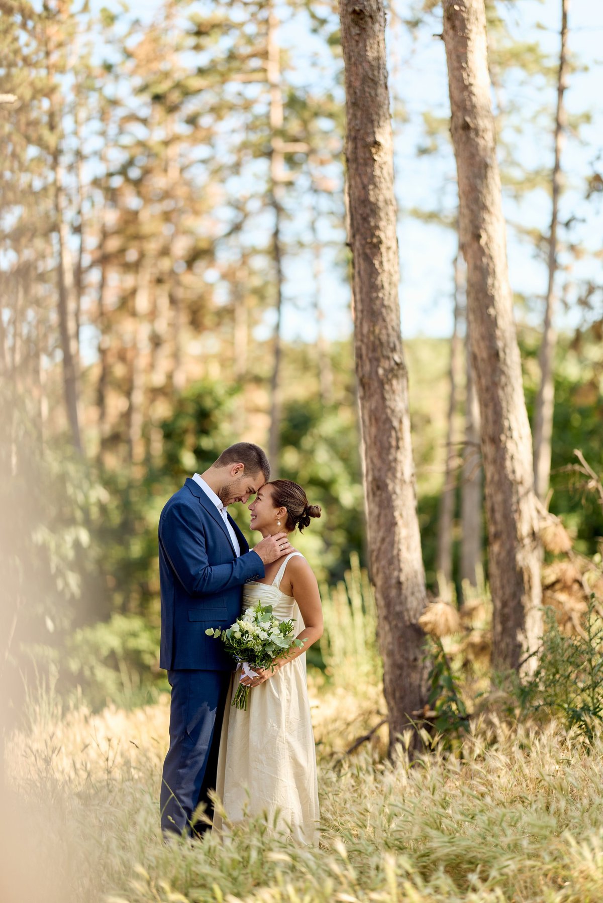Bride and groom sharing an intimate moment outdoors amidst a lush forest