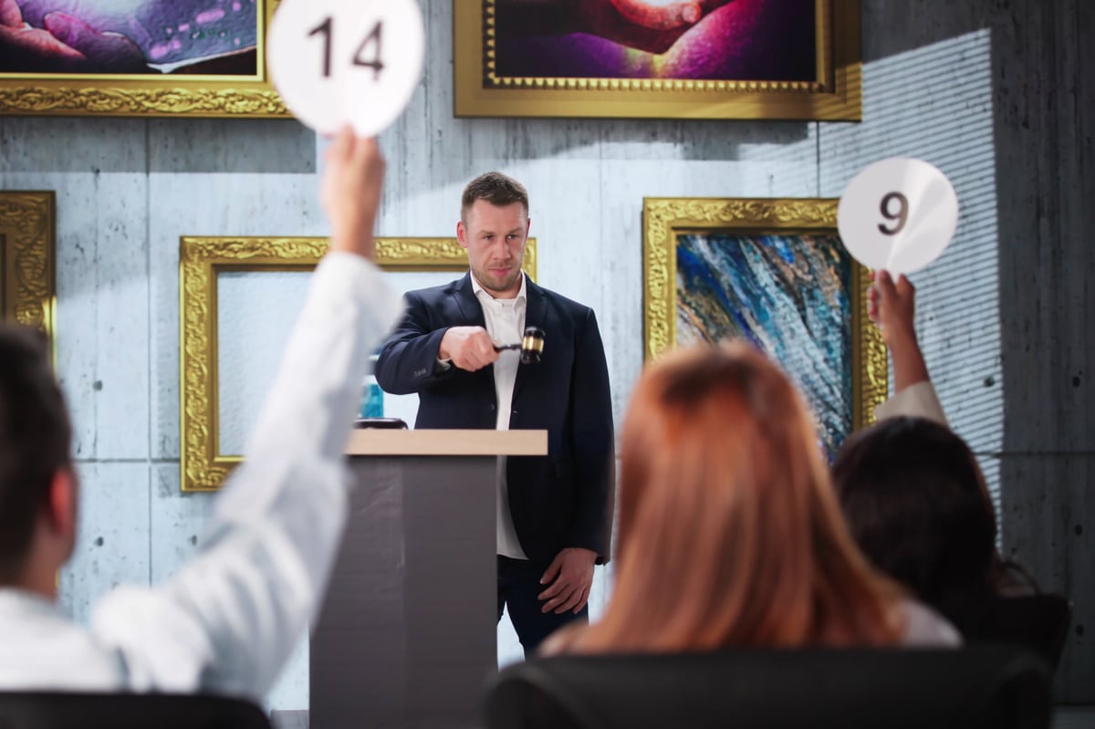 Multiracial professionals bidding on contemporary abstract artwork at a charity art auction