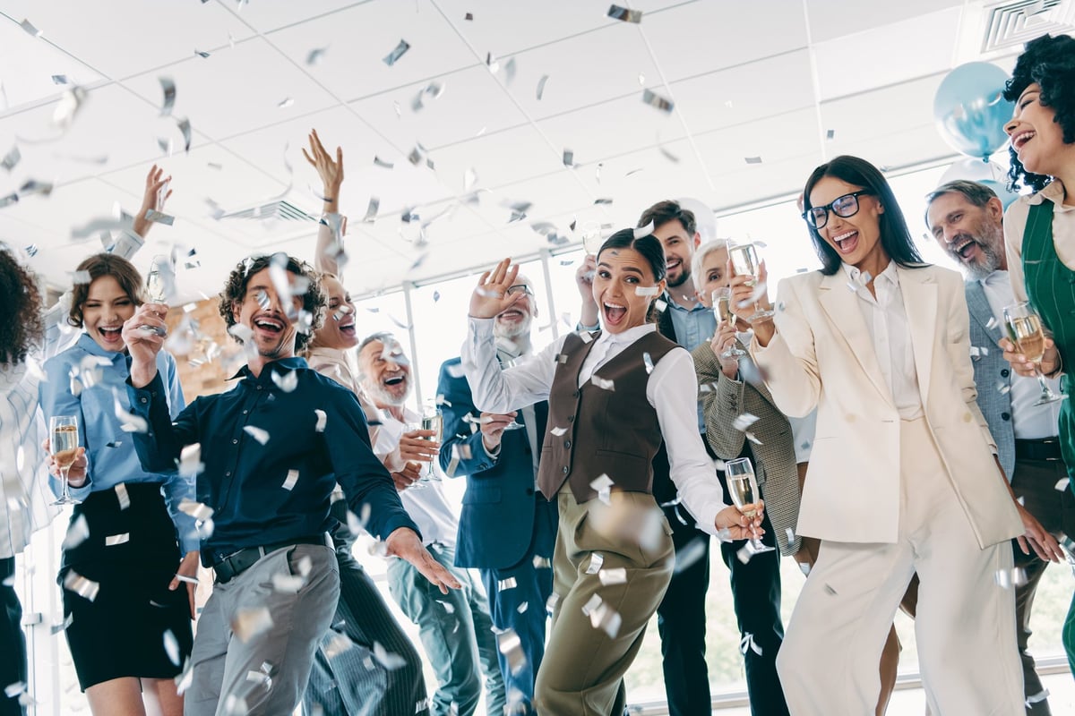 Team of diverse professionals celebrating success with confetti and bright smiles in office