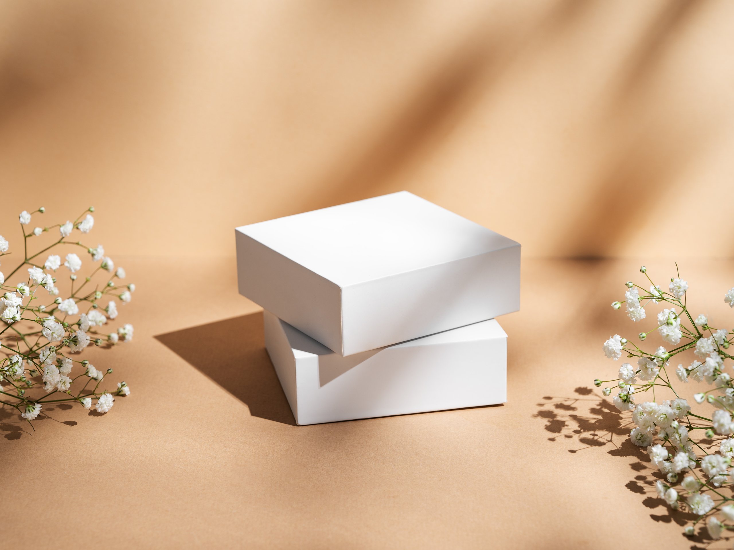 Two white square box on a beige background with gypsophila flowers