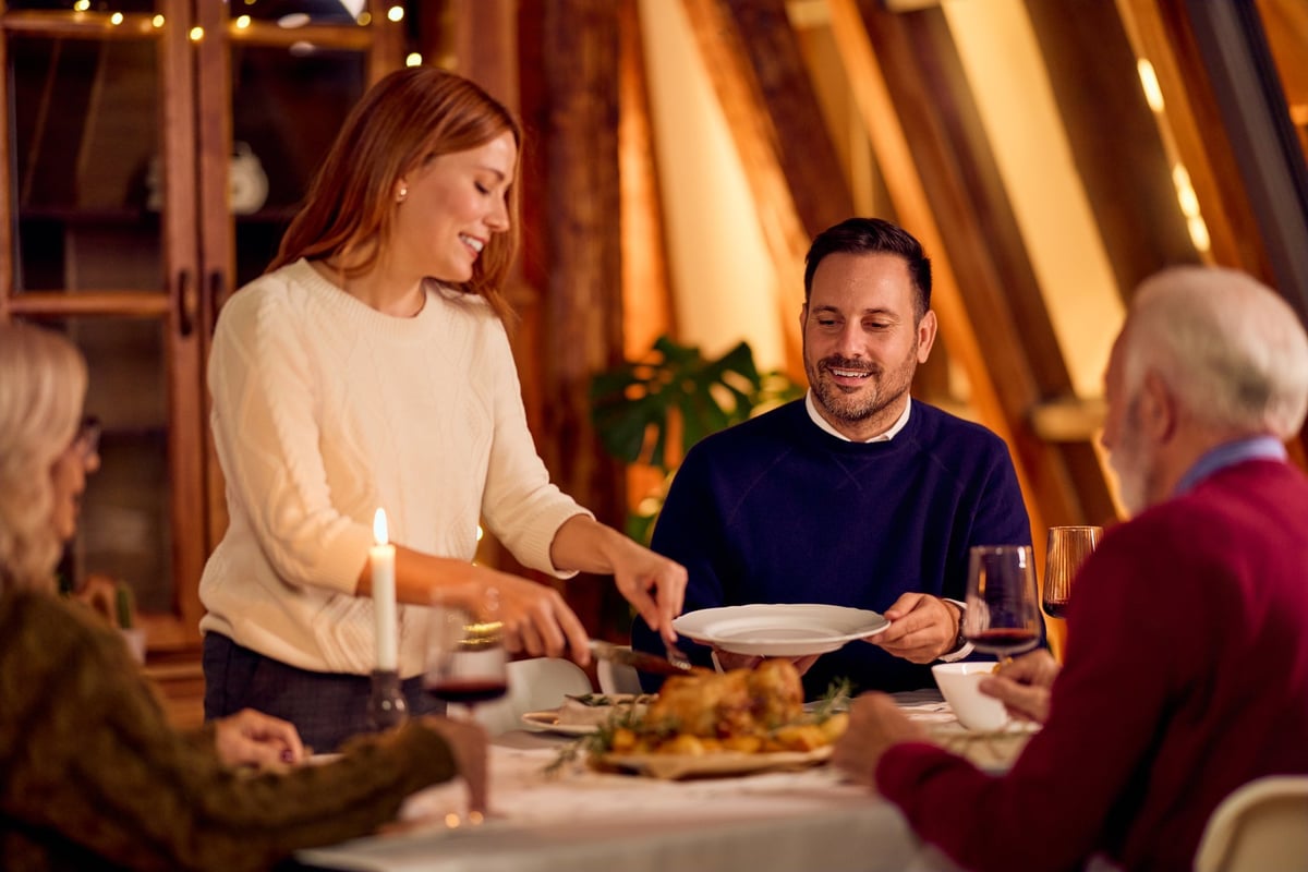 Warm candlelit family dinner scene with smiling guests sharing festive meal