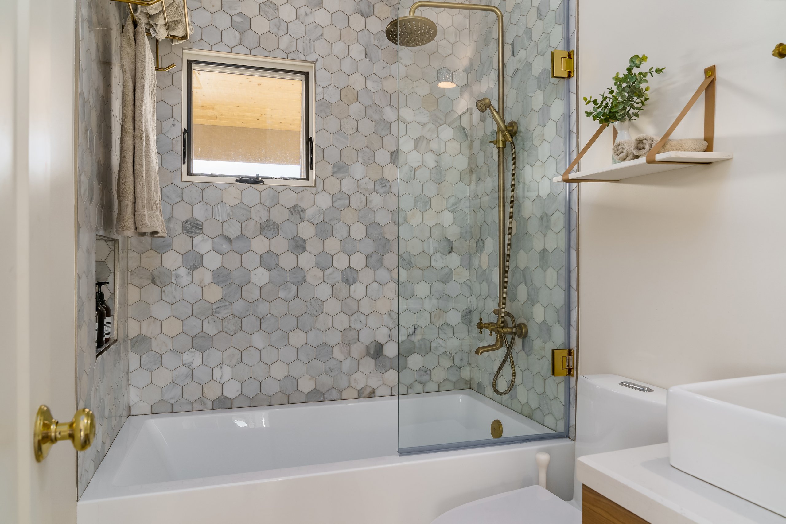 Modern bathroom in white with hexagonal tile and gold brass fixtures