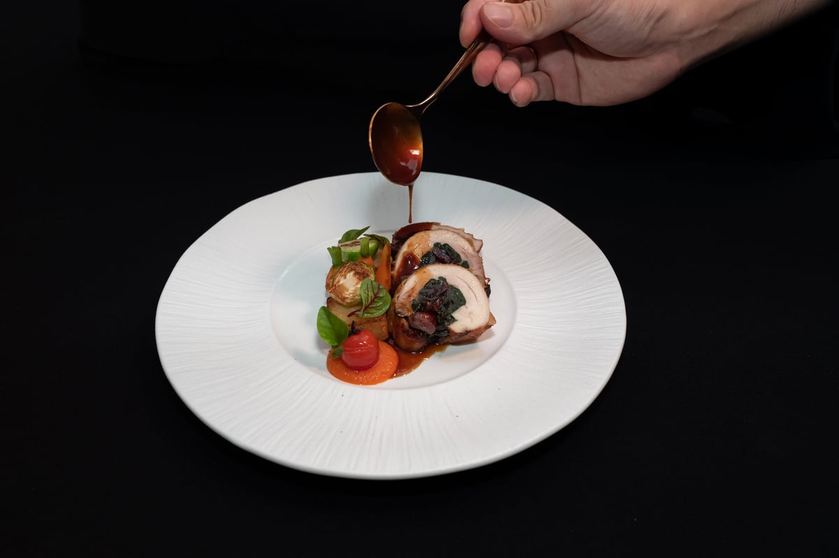 A chef delicately garnishing a beautifully plated gourmet meal