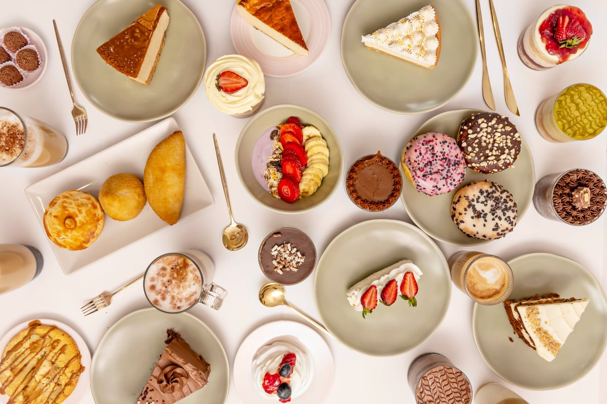 A selection of Latin American desserts: tres leches with fruit, glazed alfajores, and swirled churros with chocolate dippers