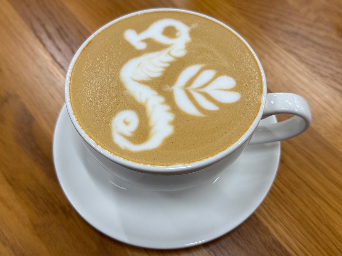 Close-up view of hot coffee with decorative latte art in a white cup on a wooden table