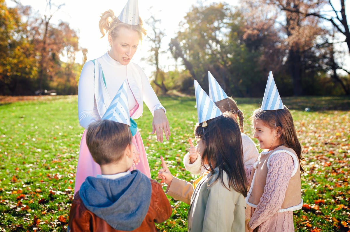 Female animator playing with a group of children at an outdoor birthday party